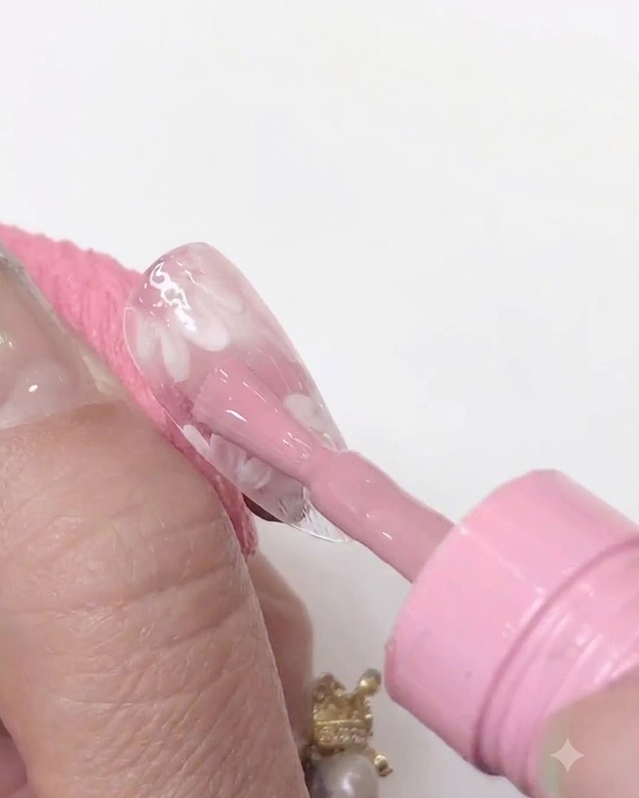 Una mini lámpara de uñas UV/LED sostenida de cerca sobre una punta de uña transparente para curar la capa de gel rosa aplicada.