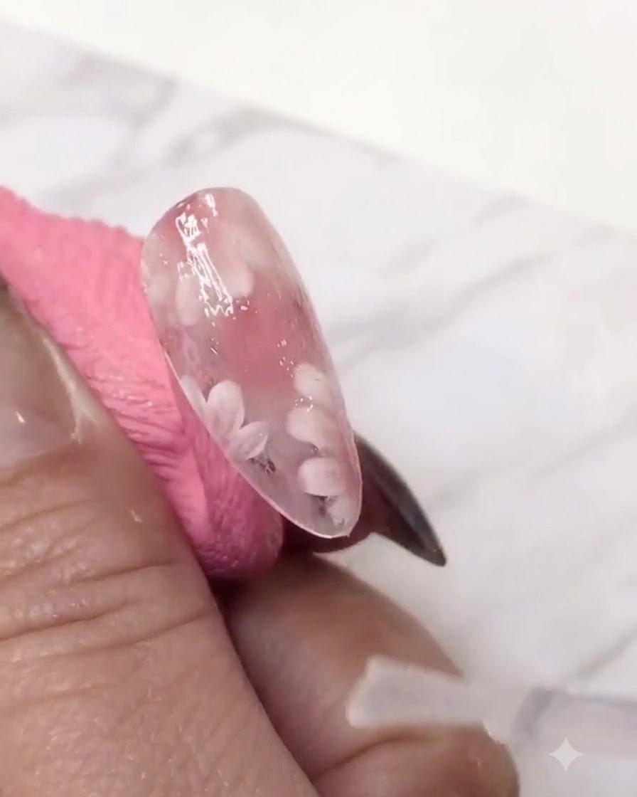 Un pincel delineador fino que agrega una segunda capa de pétalos de margaritas blancas sobre la capa de gel teñida de rosa para dar profundidad.