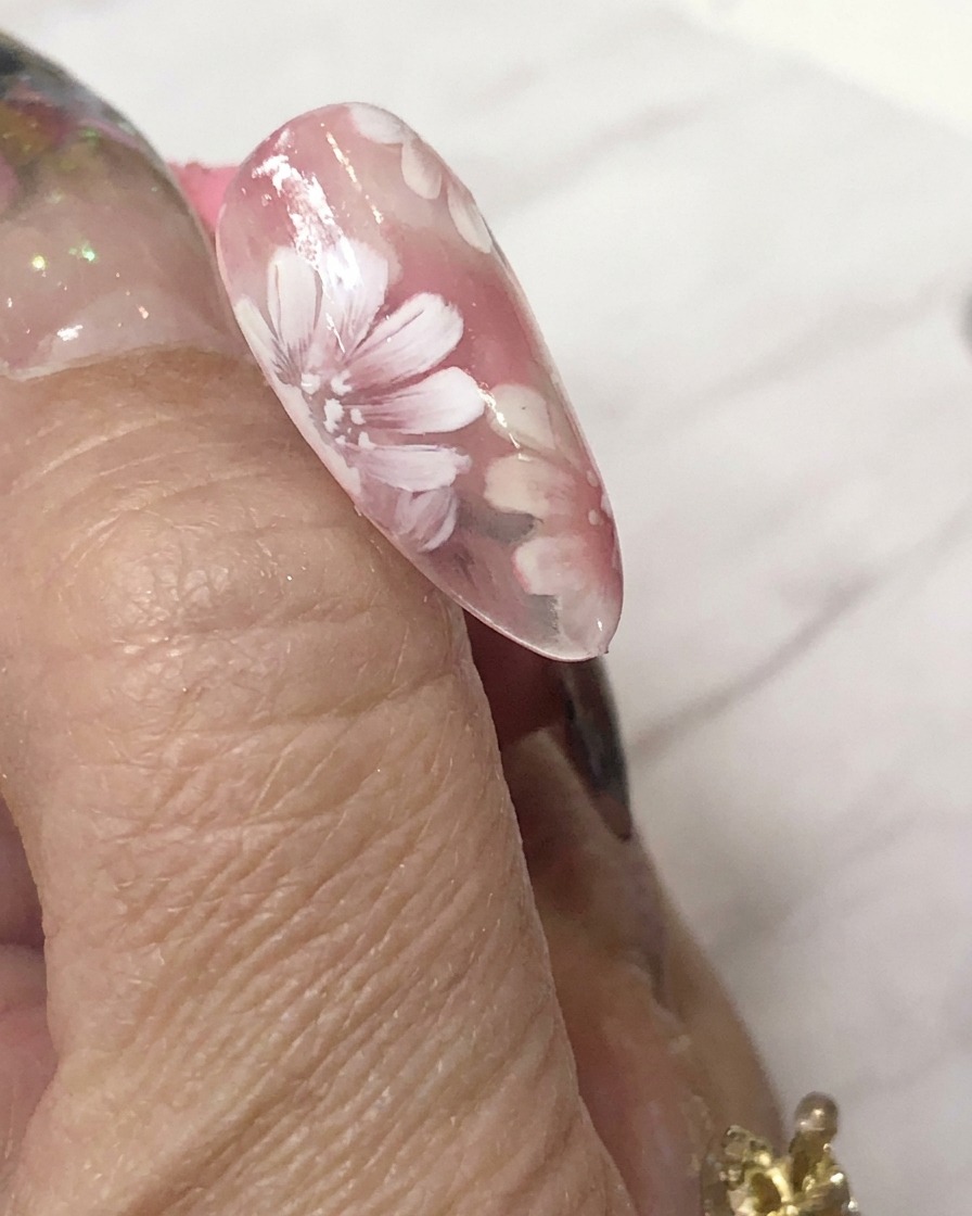 Una mini lámpara de curado LED posicionada directamente sobre una uña decorada para curar el arte en gel.