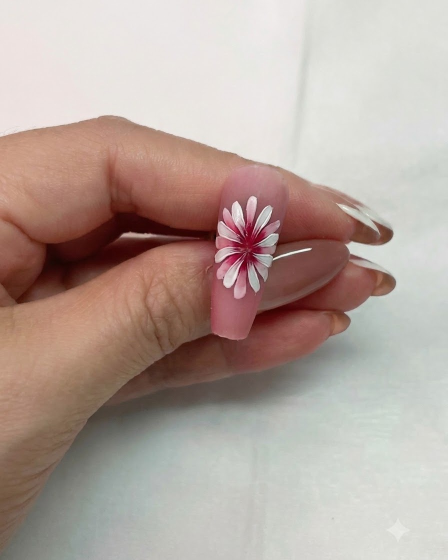Un diseño de arte de uñas de margarita blanca de doble capa completado sostenido para mostrar el efecto dimensional 3D.