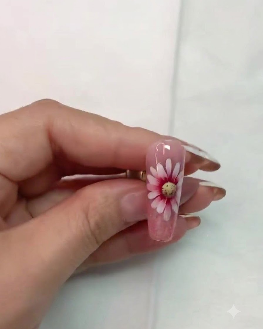 Un pincel delineador fino perfilando y refinando cuidadosamente los detalles alrededor del centro de la flor de margarita.