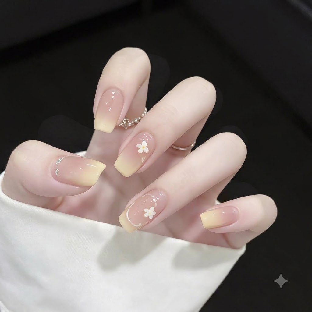 Primer plano de uñas cuadradas con puntas en degradé amarillo, detalles de contorno estilo francés en blanco fino y pequeños lunares.