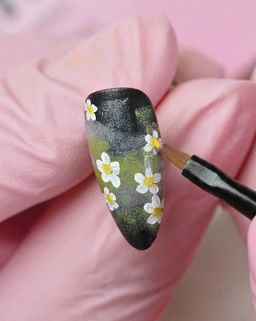 Un pincel plano alisando una capa de esmalte en gel blanco lechoso translúcido sobre la superficie de la uña.
