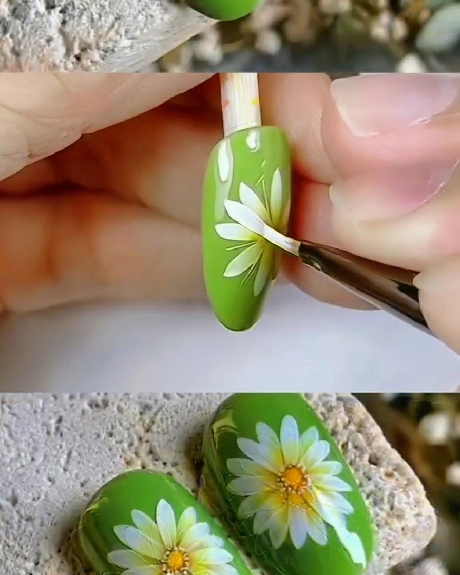 Un pincel de detalles fino retocando los nítidos pétalos blancos de un diseño de arte de uñas de margarita.