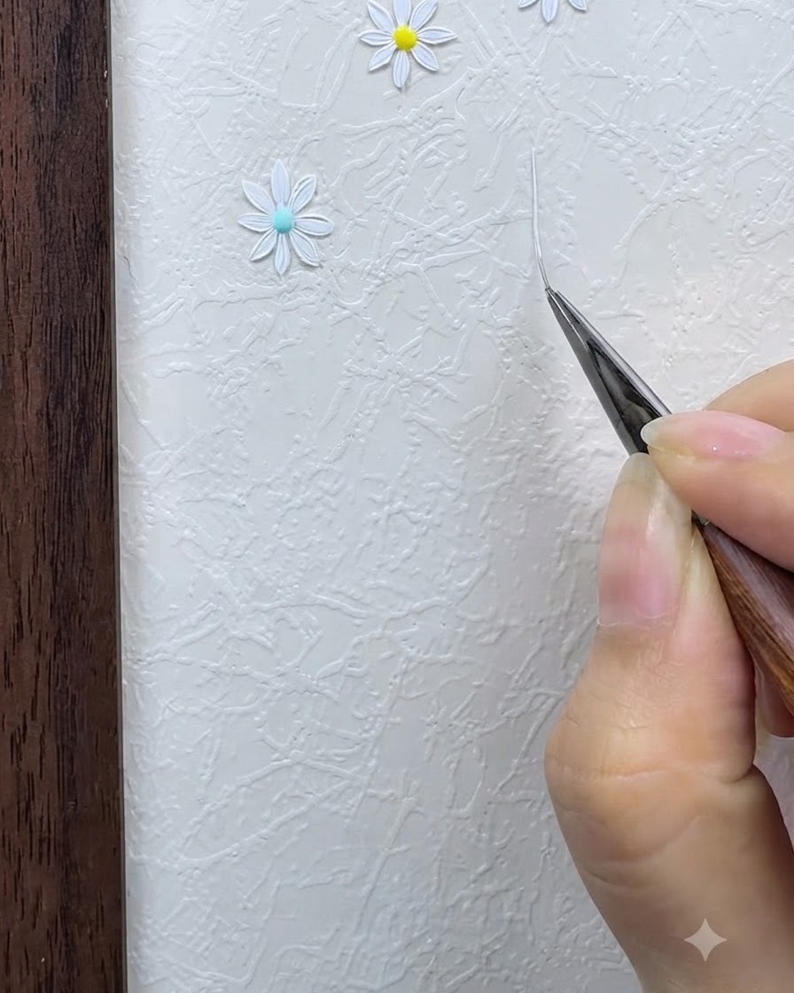Un pincel delineador fino dibujando una rejilla delgada en forma de estrella blanca sobre una superficie texturizada.