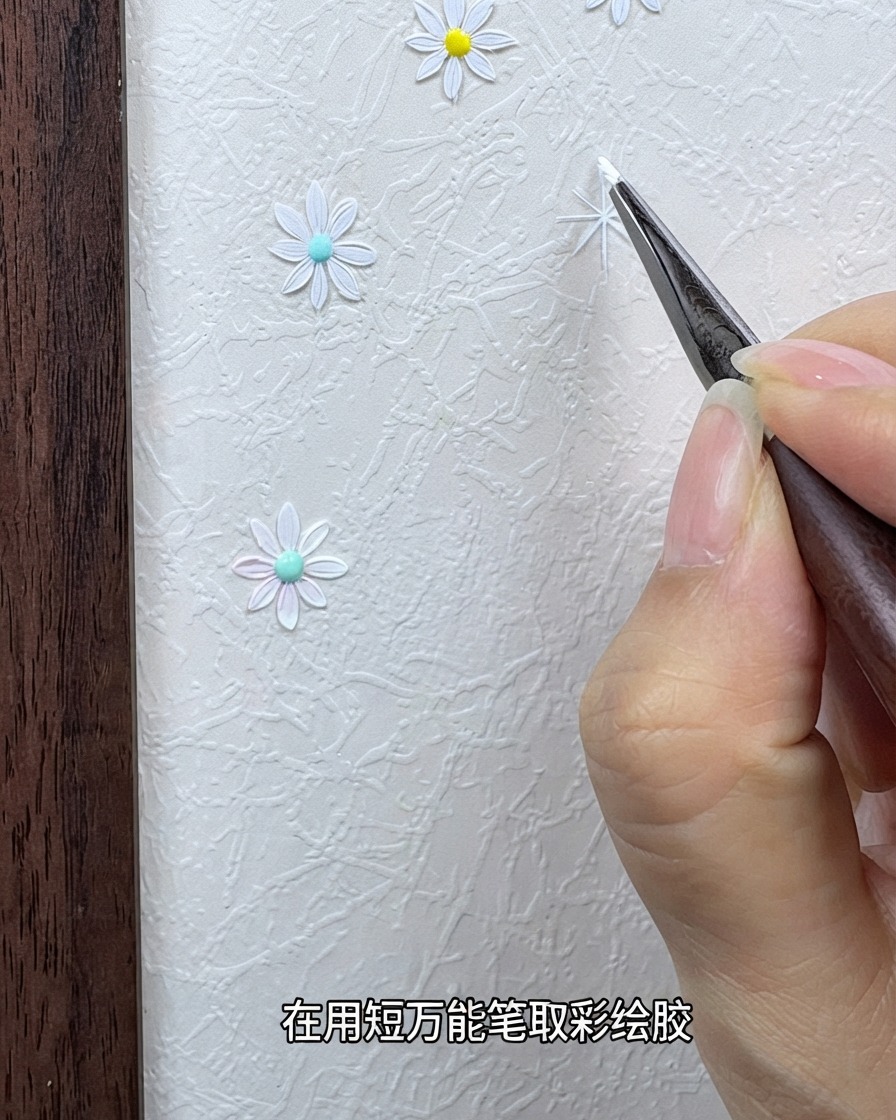 Una mano sosteniendo un pincel de detalle fino cargado con gel de pintura blanca cerca de un fondo texturizado.