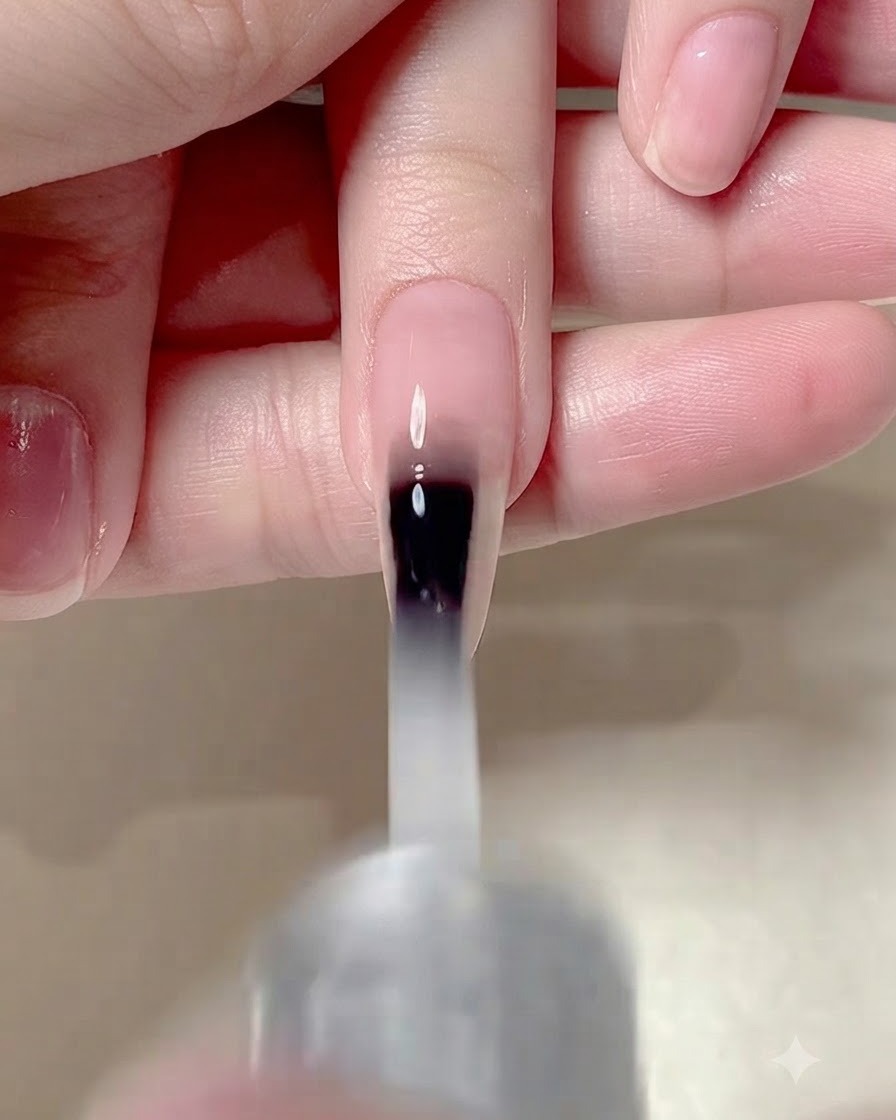 Un pincel de uñas aplicando una capa superior mate sobre toda la superficie de una uña manicurada.