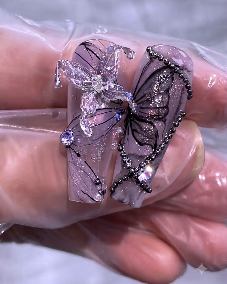 Primer plano de un juego terminado de diseños de arte de uñas con mariposas y cadenas moradas en puntas de uñas transparentes largas.