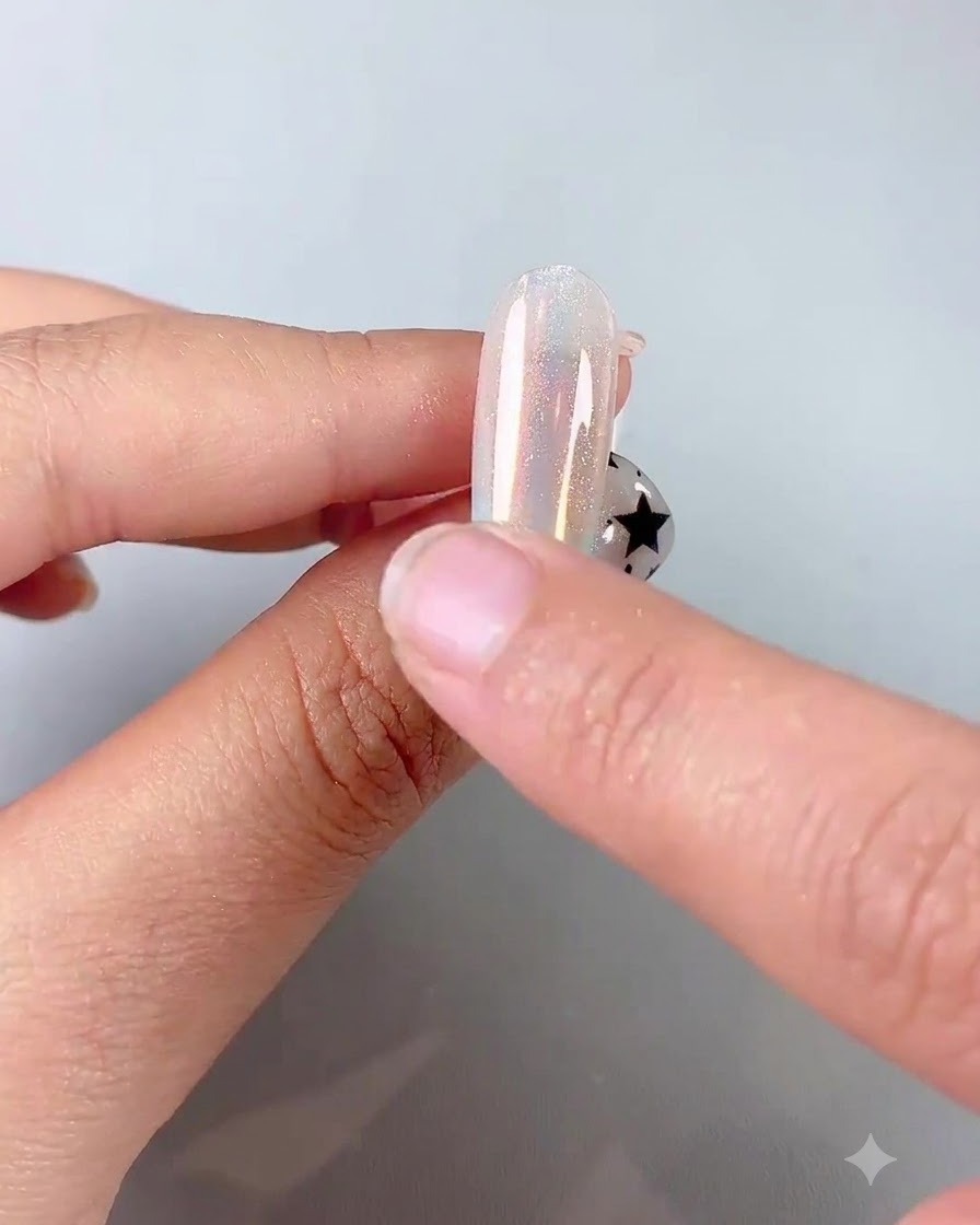 Un dedo usando un aplicador de esponja de silicona para frotar polvo cromado iridiscente sobre una uña brillante.
