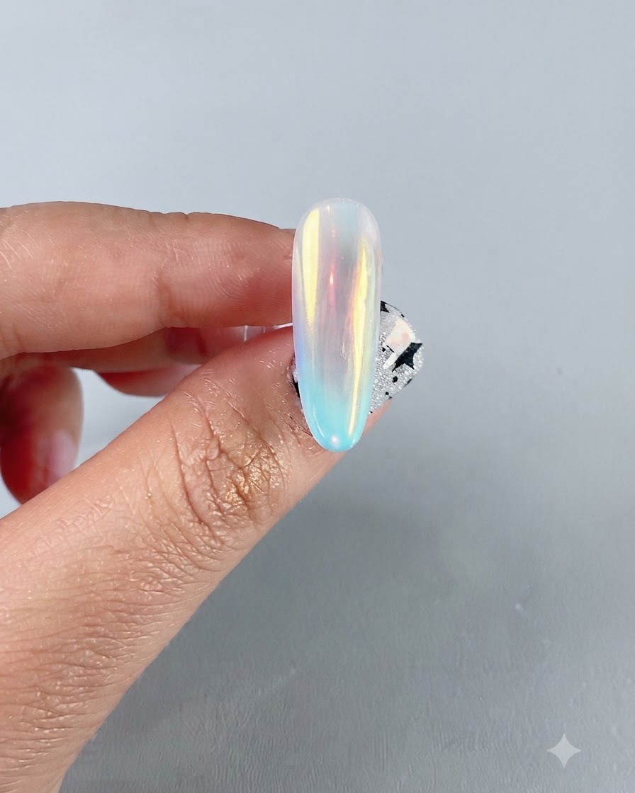 Primer plano de una uña de cromo aurora iridiscente terminada que muestra un reflejo de espejo multicolor vibrante.