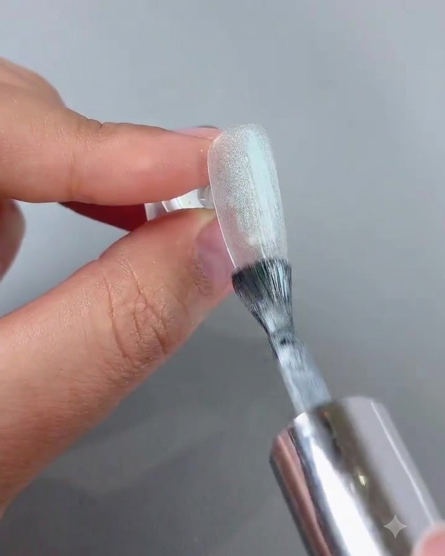 Una varita magnética sostenida cerca de una uña de gel cat-eye brillante para formar un efecto de luz esférico y brillante.