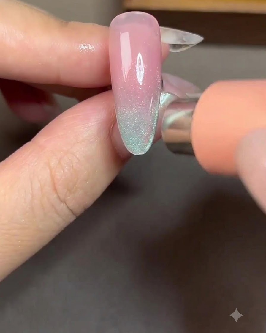 Un imán posicionado en el lado derecho de una uña para atraer las partículas cat-eye hacia una franja lateral brillante.