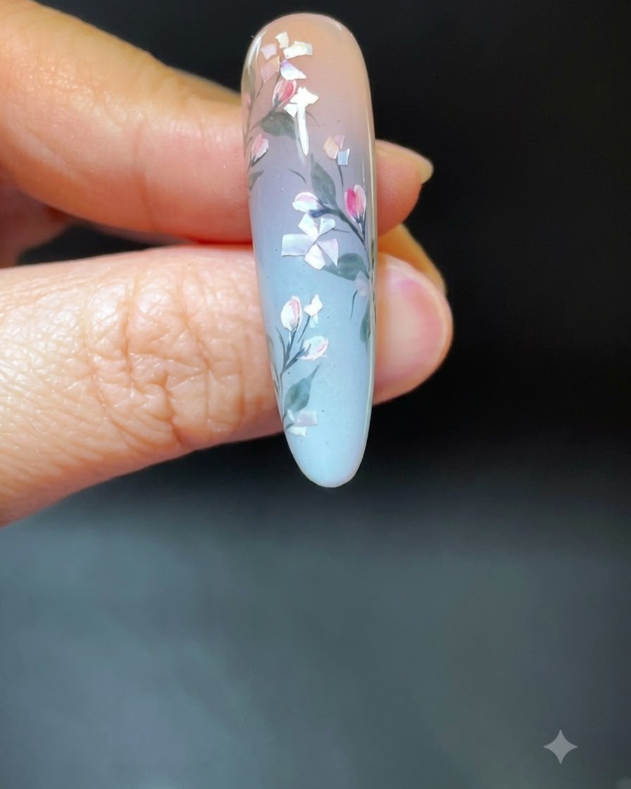 Una mano con arte de uñas floral de conchas terminado colocada dentro de una lámpara de curado UV/LED blanca.