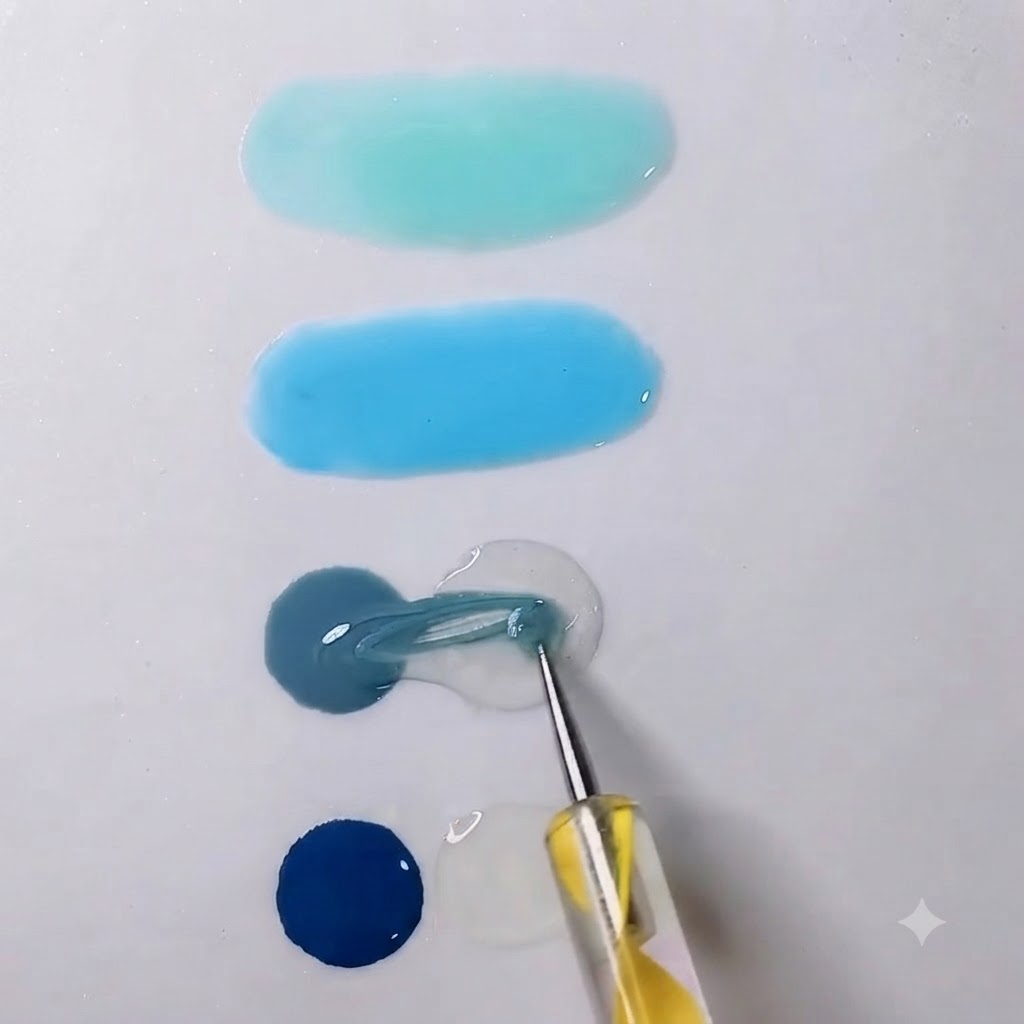Una herramienta de mezcla arrastrando gel gris hacia una gota vecina de gel transparente en una paleta blanca.