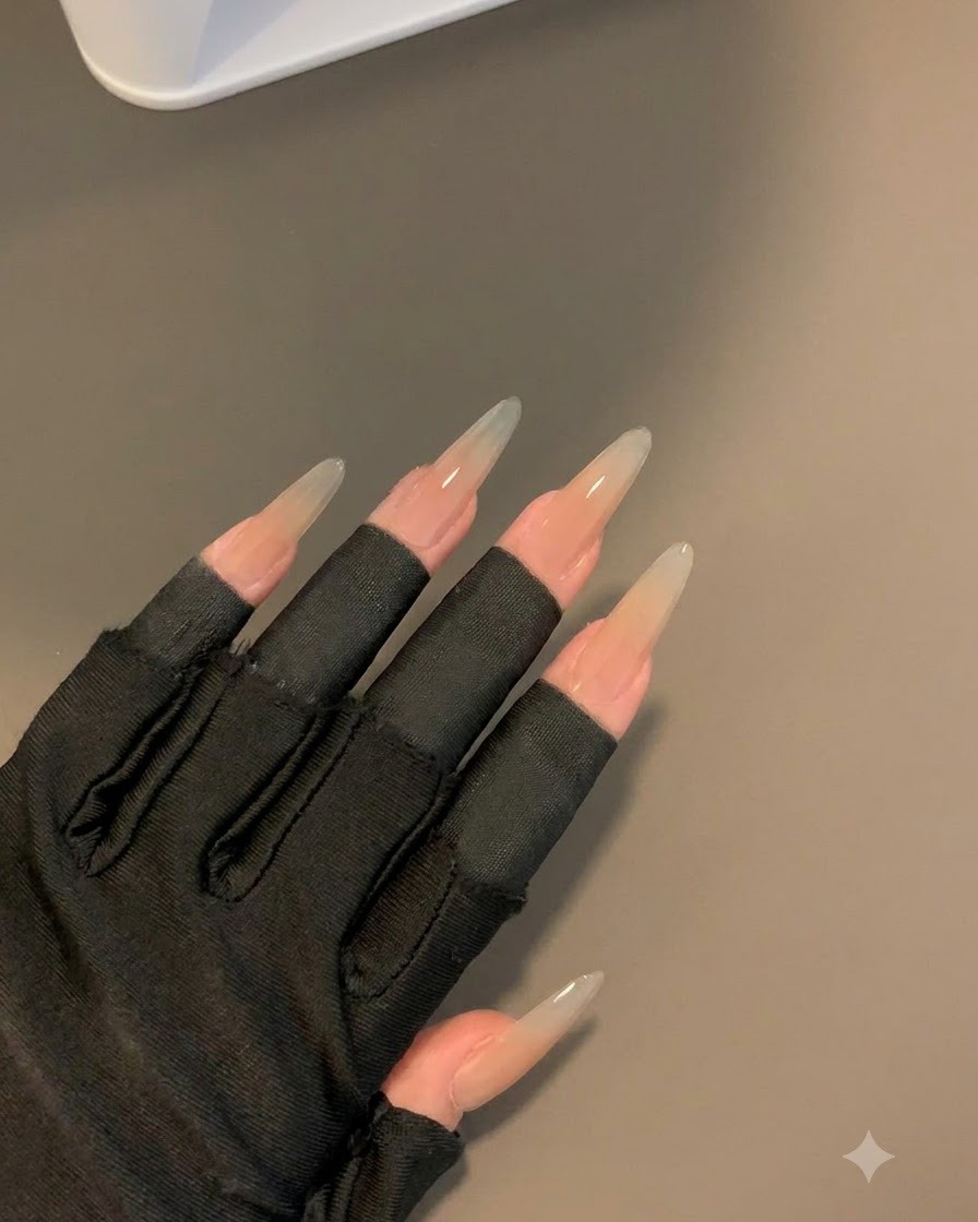 Una mano con guante negro y mangas cortadas mostrando las uñas curadas tras 30 segundos bajo la lámpara.