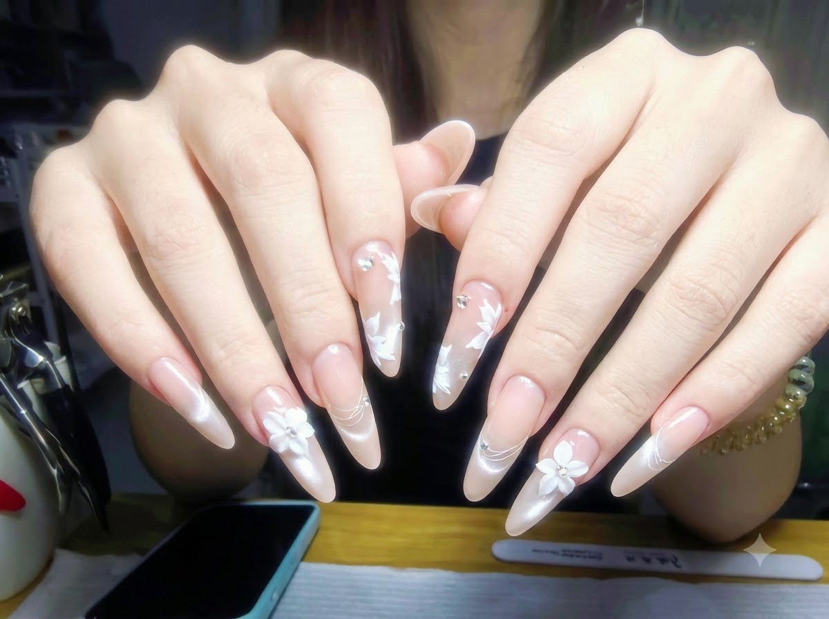 Manos descansando sobre una mesa de manicura con frascos de esmalte de uñas y herramientas profesionales dispuestas ordenadamente al fondo.
