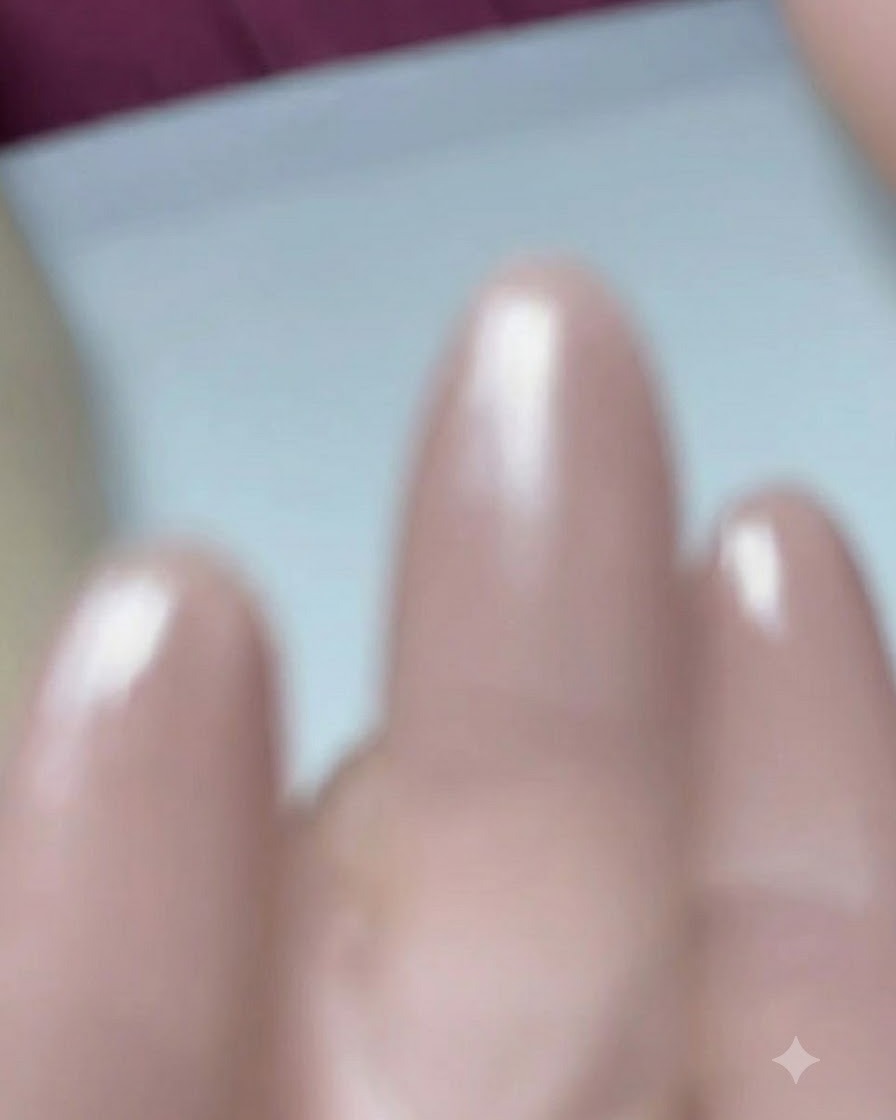 Primer plano de un pincel aplicando gel base sobre una uña prepreparada con forma almendrada.