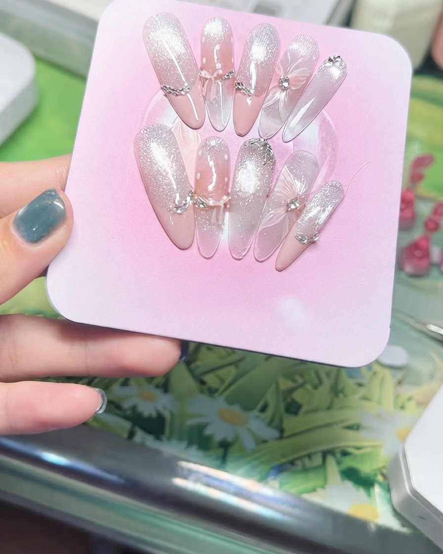Una mano inclinando un expositor rosa para mostrar las partículas brillantes del ojo de gato magnético capturando la luz.
