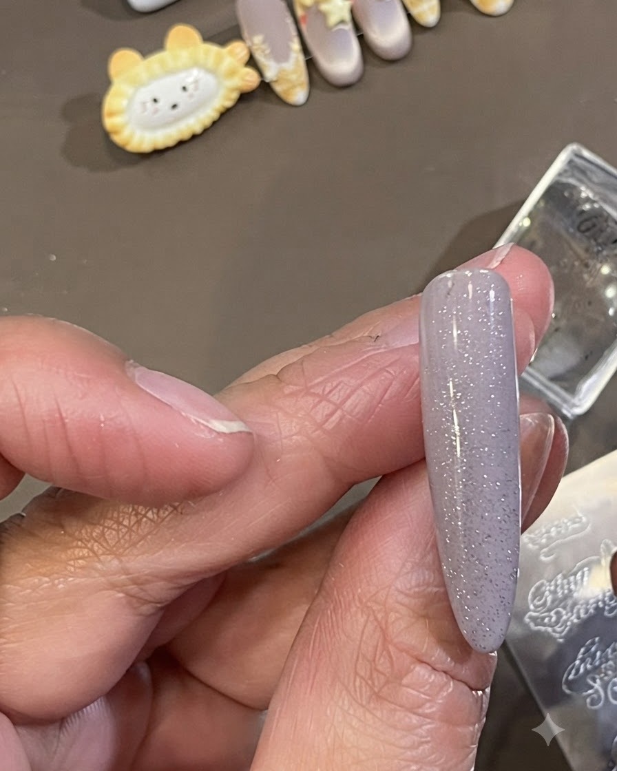 Un pequeño pincel de limpieza que limpia el exceso de esmalte de estampación oscuro de la piel que rodea el costado de una uña arreglada.