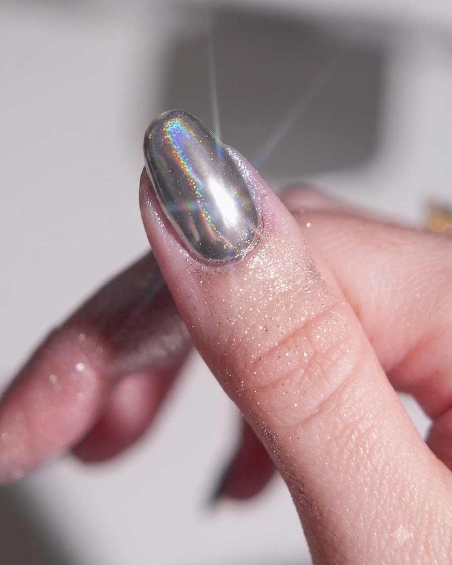 Dedo con base de gel negra curada siendo frotado con polvo cromado plateado utilizando un aplicador de esponja de silicona.