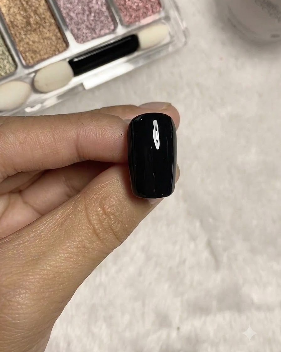 Un pincel delineador largo dibujando finas líneas tridimensionales sobre la superficie de la uña con textura negra.