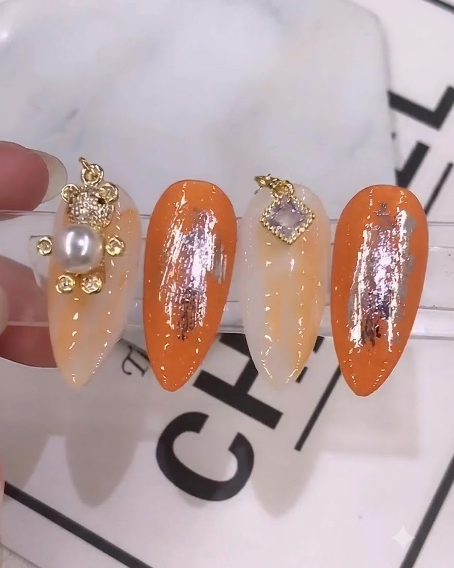 Un primer plano detallado de un pincel de uñas aplicando un color de gel mezclado en tonos naranja vibrante sobre una uña preparada.