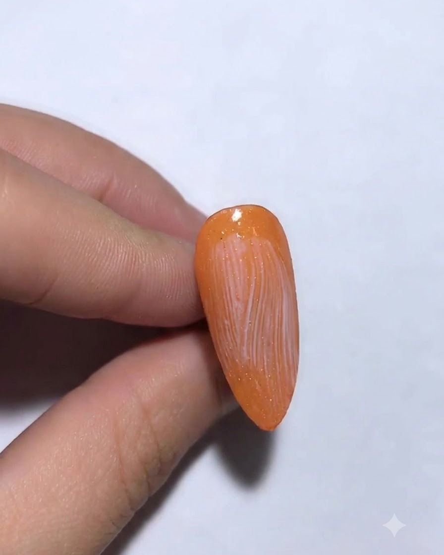 Foil de transferencia plateado siendo aplicado y presionado sobre una uña.