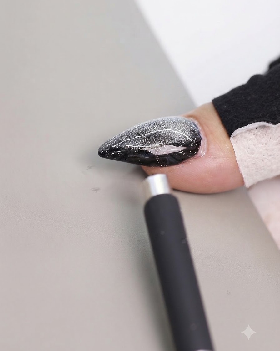 Una herramienta magnética posicionada cerca del borde lateral de una uña cat eye decorada para cambiar el reflejo.