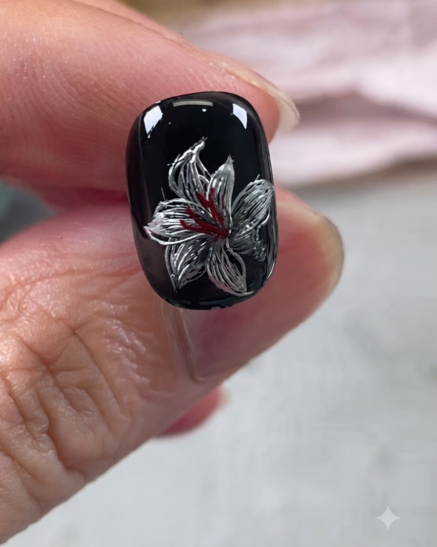 Diseño de uñas con lirio metálico terminado bajo una capa de brillo transparente.