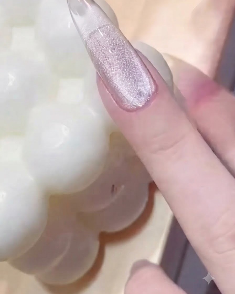 Una mano presionando una herramienta de anillo con cuentas metálicas sobre una uña con capa de gel brillante para crear impresiones texturizadas.