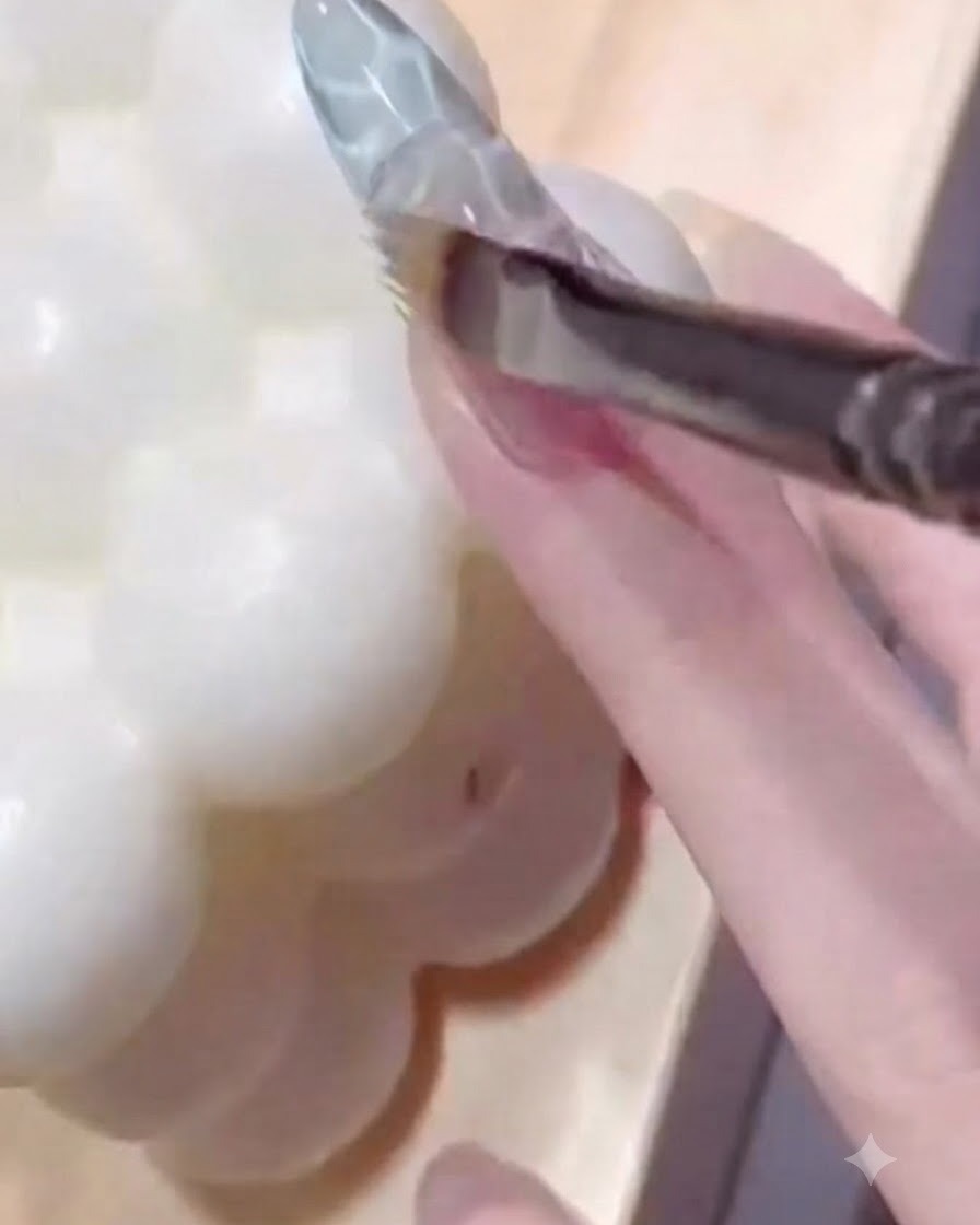 Un pincel de uñas difuminando gel azul translúcido sobre una uña texturizada para crear una transición de color suave.