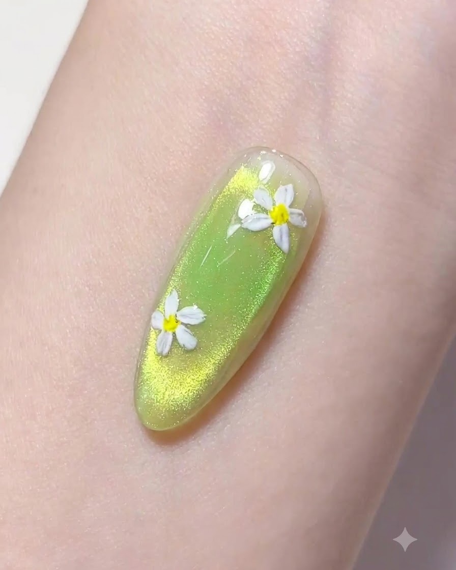 Un pincel delineador fino tomando una gota de gel de construcción transparente sobre una uña verde manicurada.