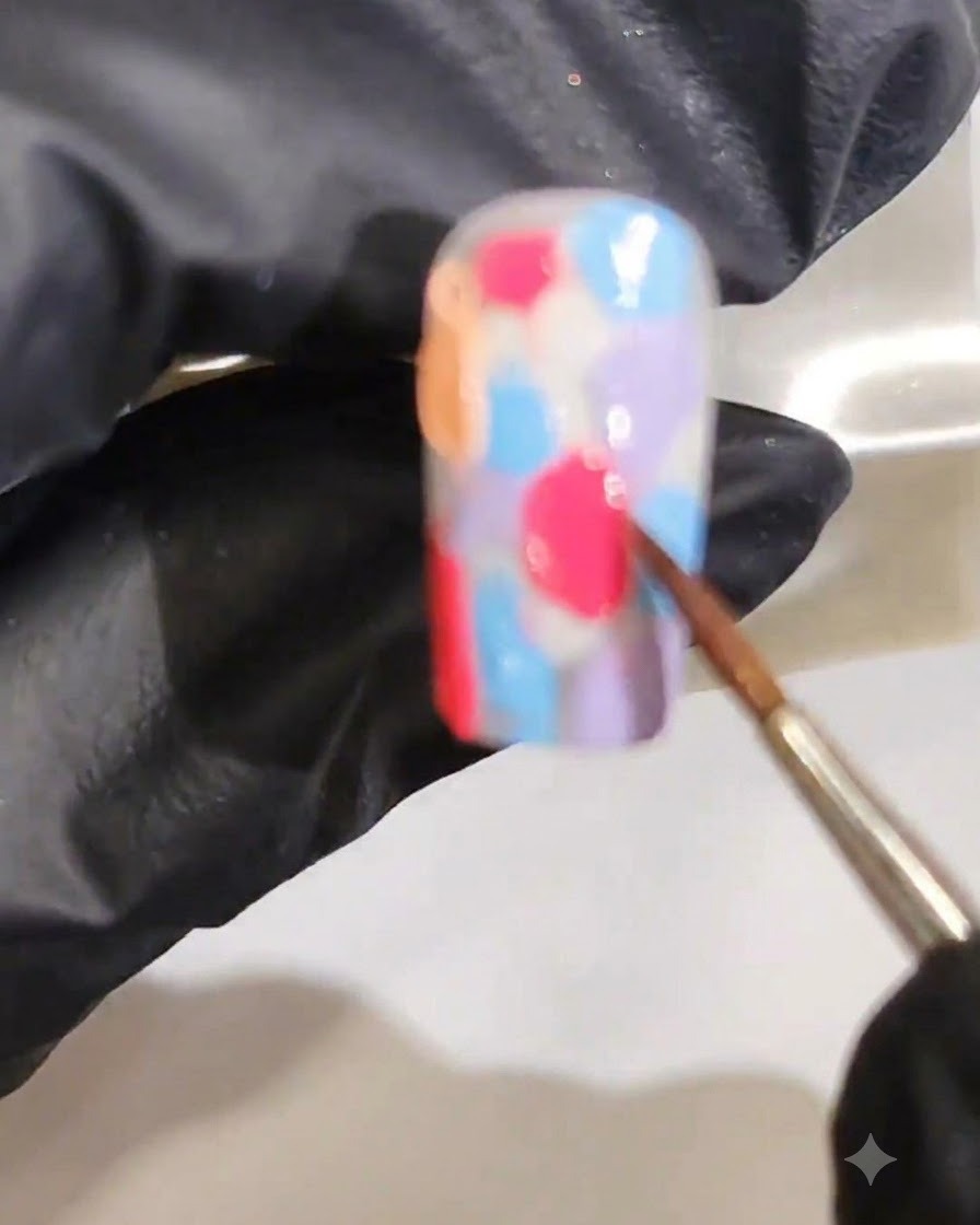Un pincel fino difuminando varios colores de gel húmedo para formar un degradado de acuarela marmoleado y suave.