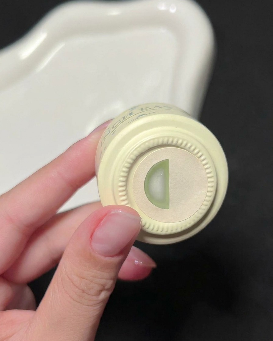 Una mano sosteniendo una botella de esmalte en gel verde de INCH EASY, mostrando la etiqueta indicadora de color en la parte superior.