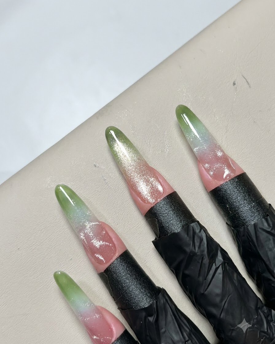 Pinzas finas colocando pequeños accesorios de cuentas metálicas sobre un patrón de arte de uñas terminado.