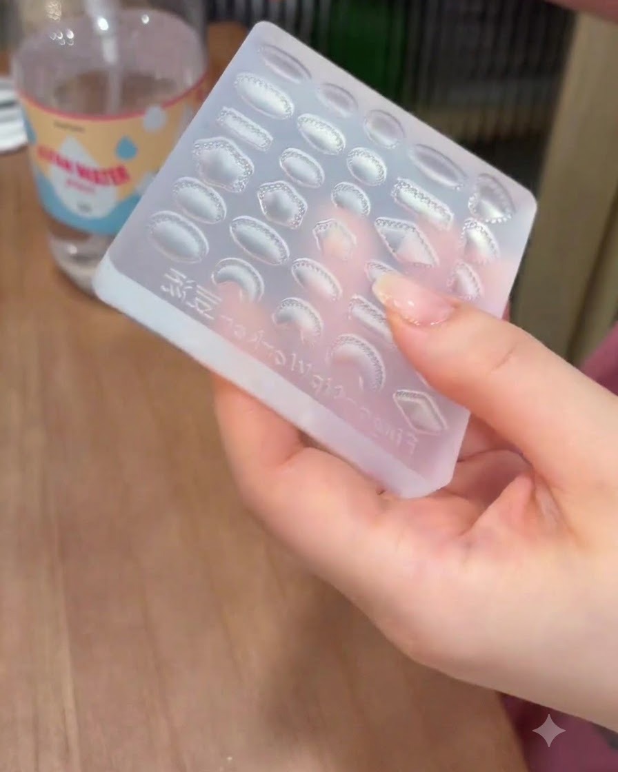 Una mano sosteniendo un molde de silicona transparente con cavidades de gemas mientras lo limpia con una toallita de limpieza.