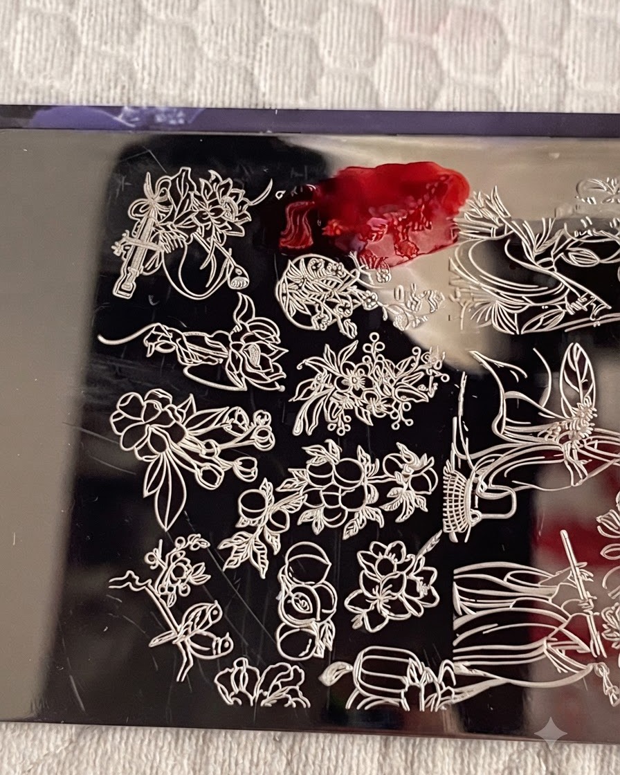 Una placa de stamping metálica con esmalte de stamping número 1 aplicado sobre el diseño de flores, y una tarjeta raspadora retirando el exceso de esmalte.